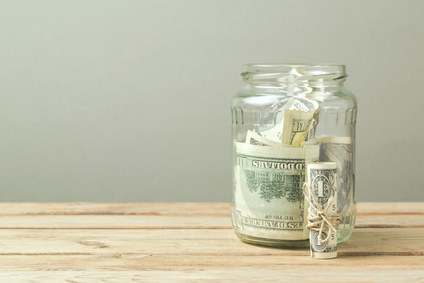 Money in glass jar on wooden table